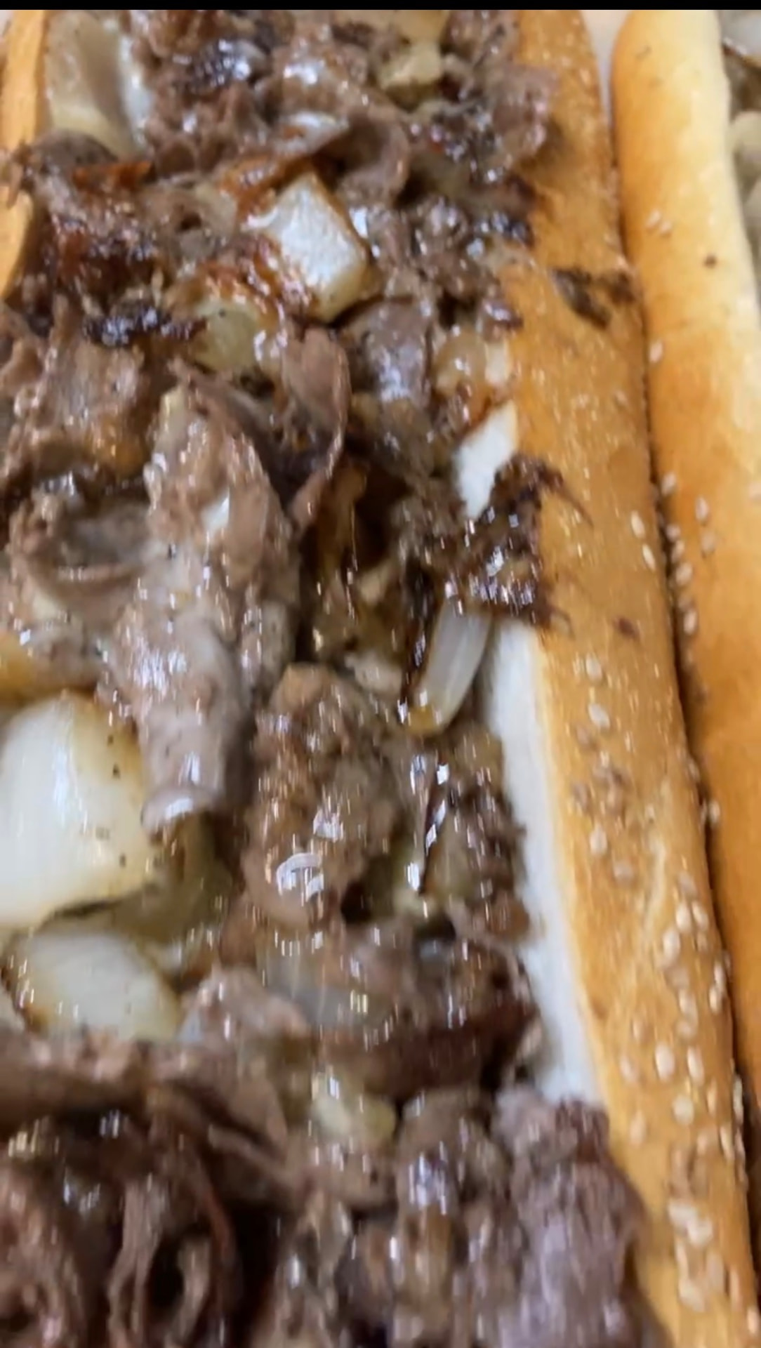 Cheesesteak on a seeded roll piled with chopped steak, melted cheese and grilled onions