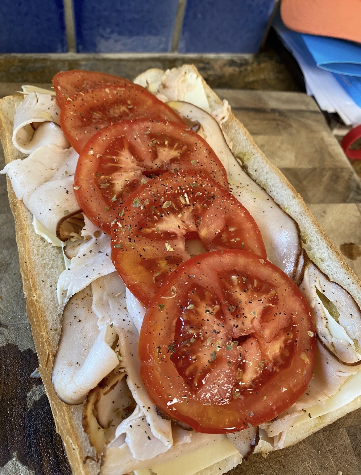 Open turkey hoagie on Italian bread layered with sliced turkey, white cheese, tomato slices, oregano and pepper